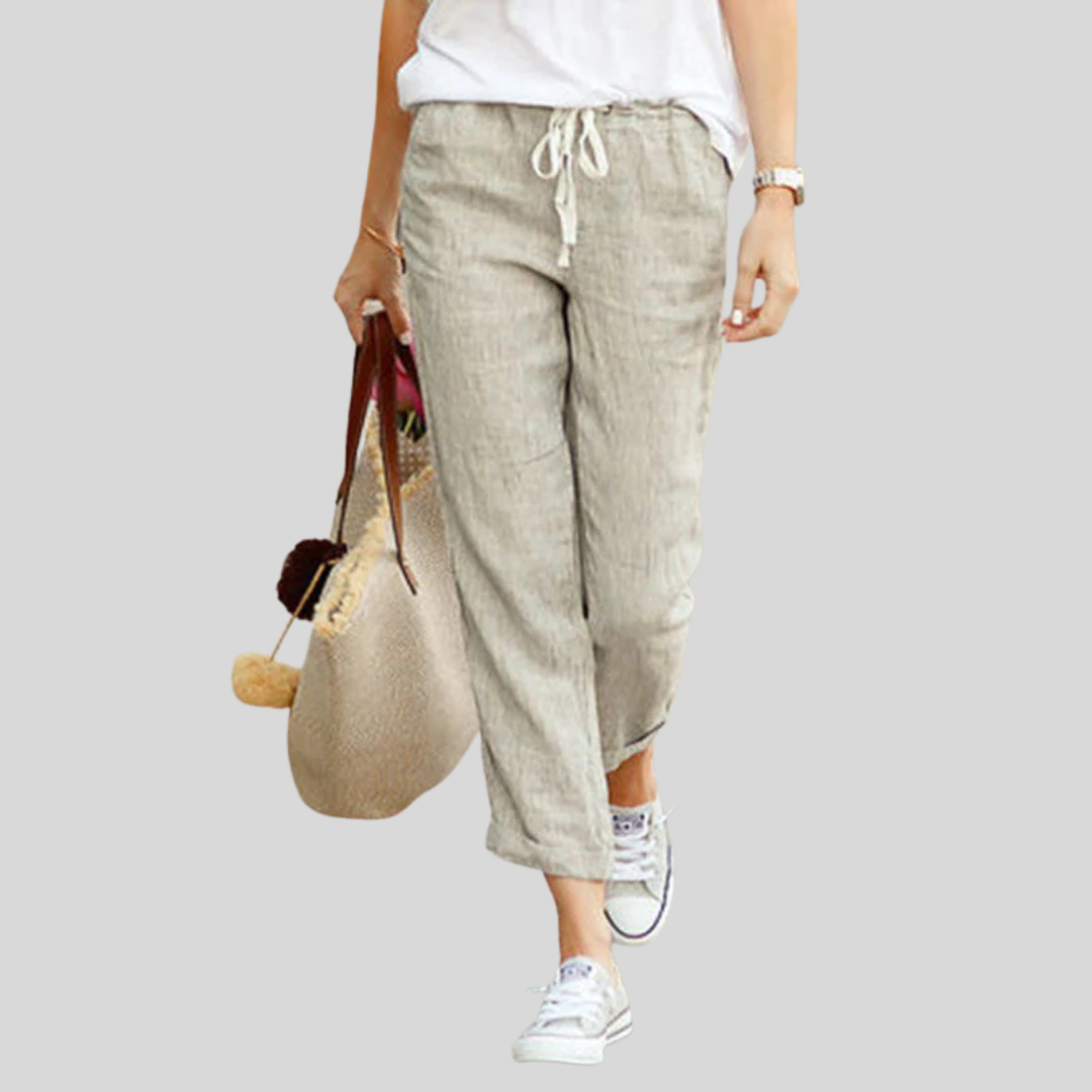 Woman wearing flared drawcord-waist pants with sneakers, walking through town.