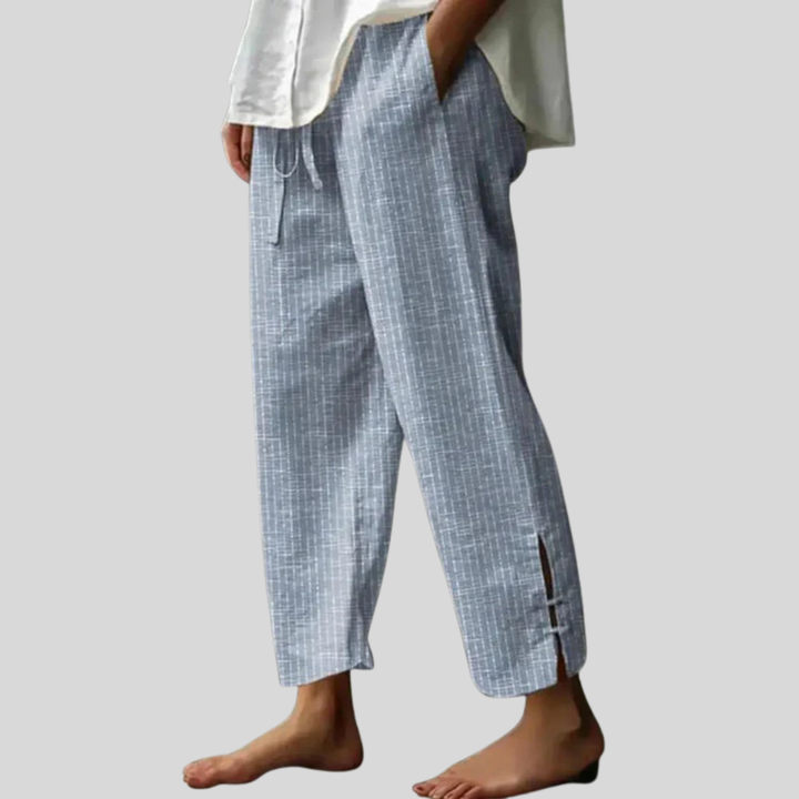 Woman wearing tapered drawcord-waist pants with sandals, standing in a sunlit garden.