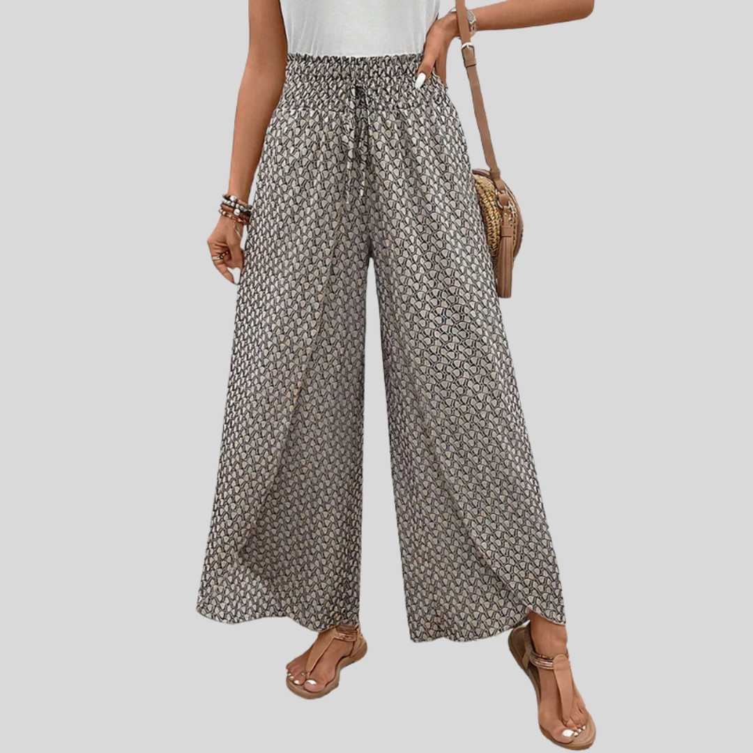 A woman wearing wide, flowing pants in a beige-and-black geometric print with an elastic drawstring waist.