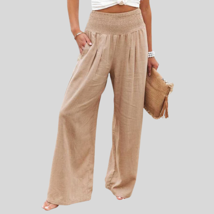 A woman walking by the sea in wide-leg beach pants with a relaxed, breezy summer look.