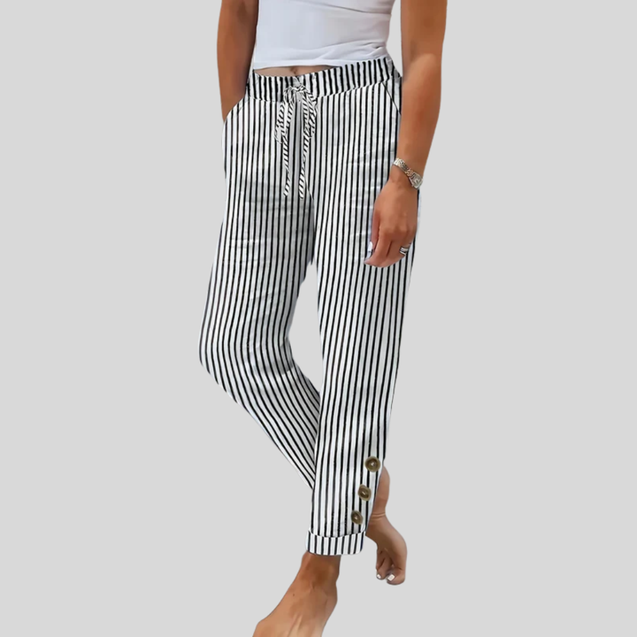 A woman wearing black vertical-striped pants with a drawstring waist and button hem detail.