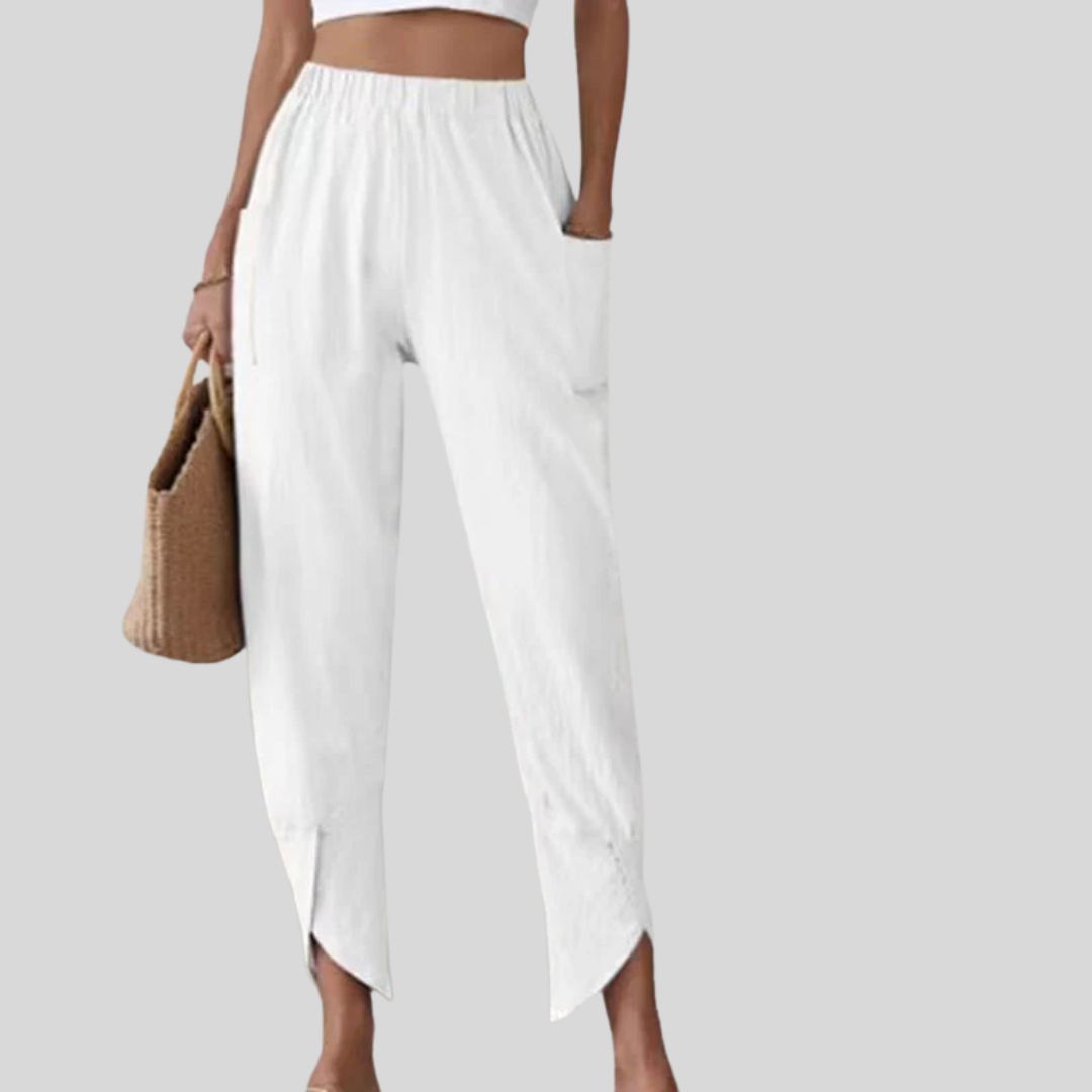 Woman wearing tapered pants with a slit hem at the ankle, walking near the coast.
