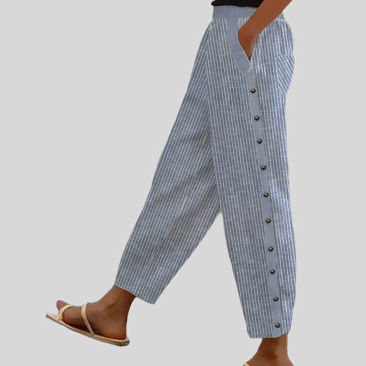 A woman wearing striped pull-on pants with a side button detail and elastic waist.