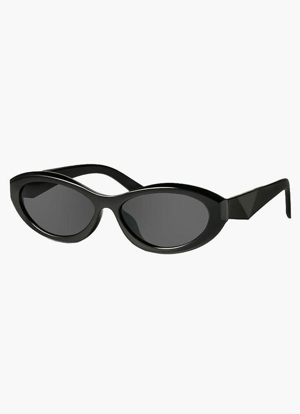 A woman wearing minimalist oval vintage sunglasses on a sunny day.