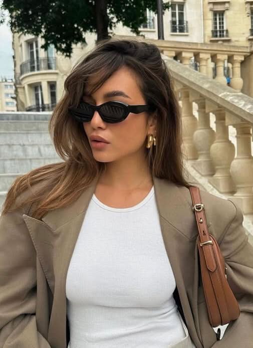A woman wearing minimalist oval vintage sunglasses on a sunny day.
