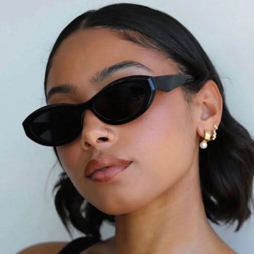 A woman wearing minimalist oval vintage sunglasses on a sunny day.
