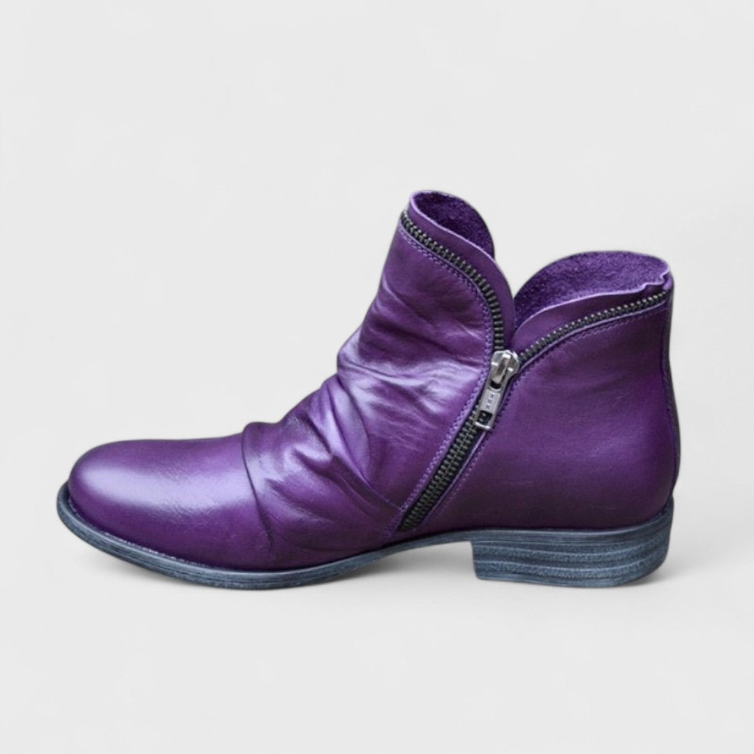 Woman wearing purple comfort ankle boots with jeans on a city street.