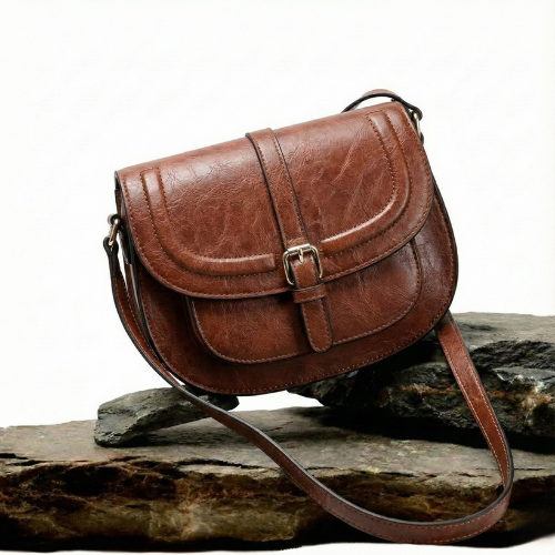 A woman carrying a crossbody satchel at her hip while out for a walk in town.