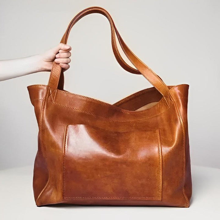 A woman carrying a roomy dark brown everyday handbag on her shoulder during a busy day.