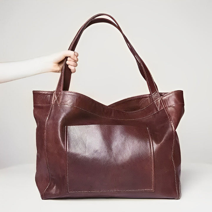 A woman carrying a roomy dark brown everyday handbag on her shoulder during a busy day.