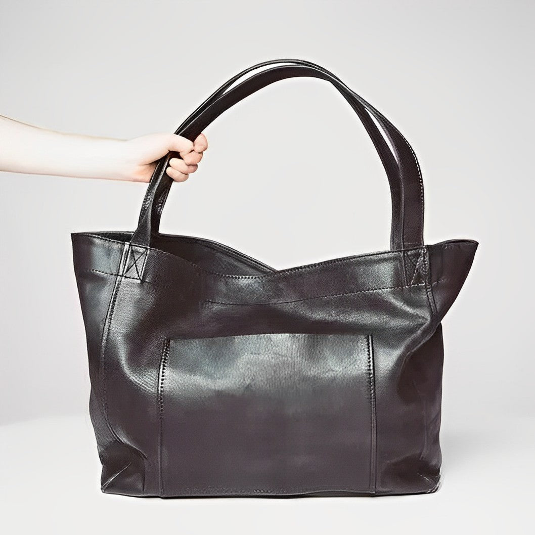 A woman carrying a roomy dark brown everyday handbag on her shoulder during a busy day.
