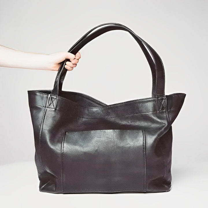 A woman carrying a roomy dark brown everyday handbag on her shoulder during a busy day.
