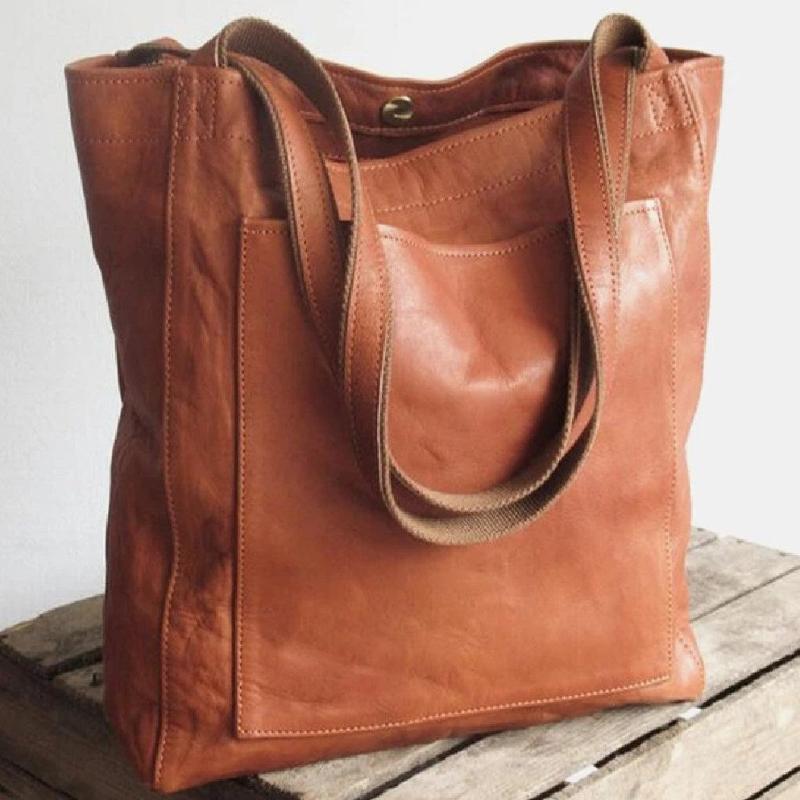 A woman holding a classic handbag with a rich finish by her side