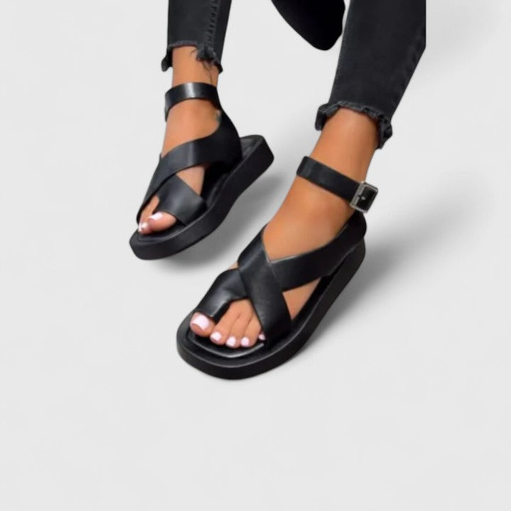 A woman walking comfortably in beige cushioned cross-strap sandals with an adjustable ankle buckle.