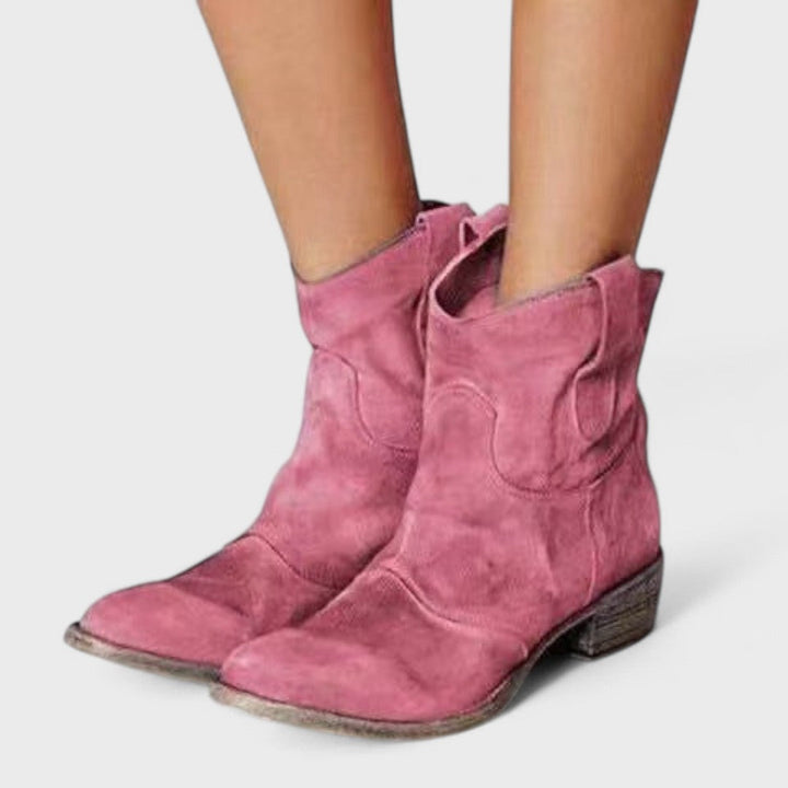 Woman wearing brown Western ankle boots with jeans, standing on a country lane.