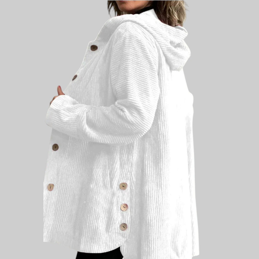 A woman wearing a hooded textured jacket outdoors in fall