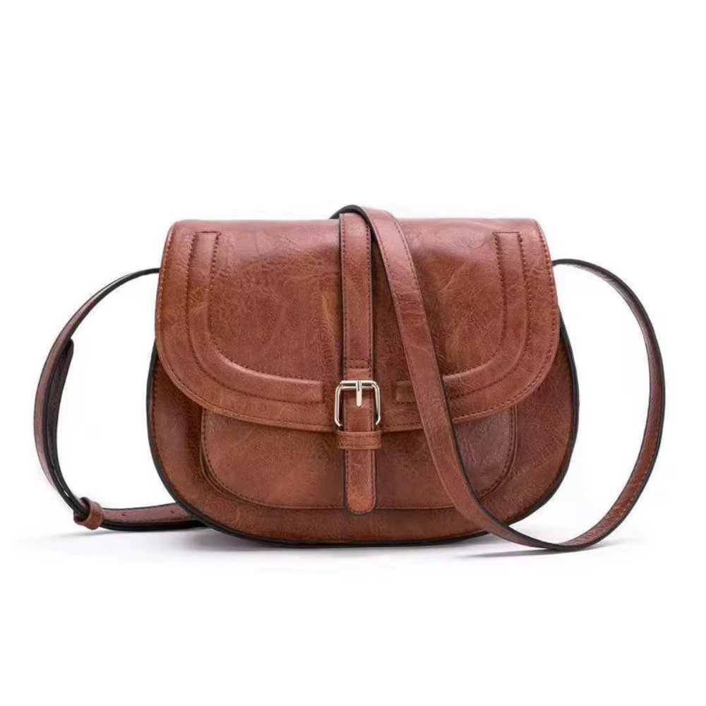 A woman carrying a crossbody satchel at her hip while out for a walk in town.