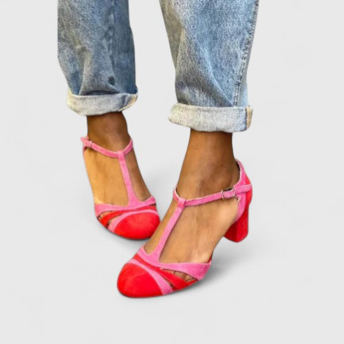 A woman wearing berry red heels with an ankle strap, stepping out in a confident evening look.