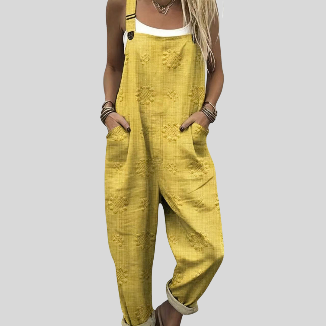 A woman wearing bright mustard-yellow overalls with a plain top, catching up over coffee.