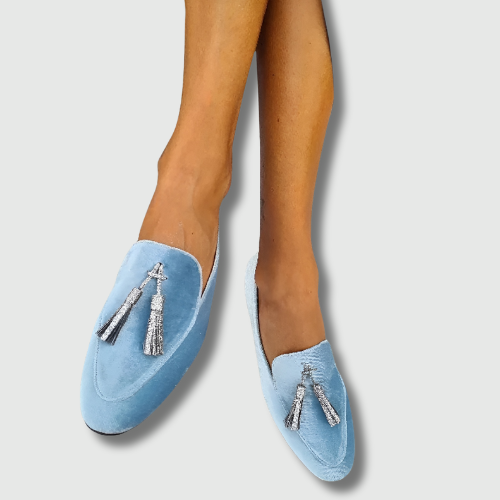 A woman wearing blue slip-on loafers with a soft finish, styled for a relaxed day out.