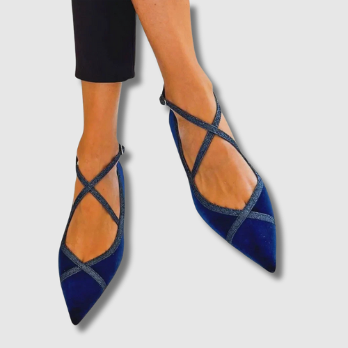 A woman wearing cobalt blue pointed flats with crossed instep straps, looking elegant and at ease.