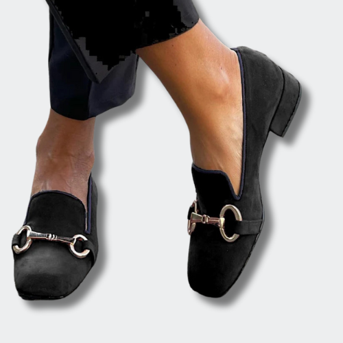 A woman wearing loafers with decorative buckle details and a smart outfit