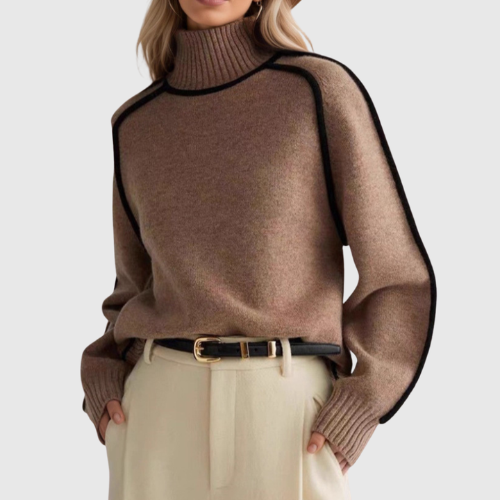 A woman wearing a funnel neck sweater with contrast piping, styled with pants for a smart-casual look.