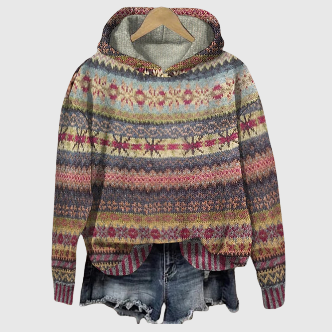 A woman wearing a retro hooded sweater in warm tones with a colourful Nordic pattern.