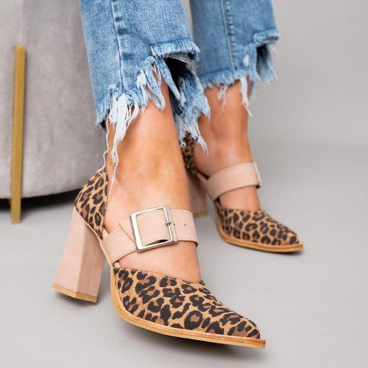 A woman wearing leopard-print pointed heels with a neutral buckled strap and block heel, stepping out in a polished outfit.