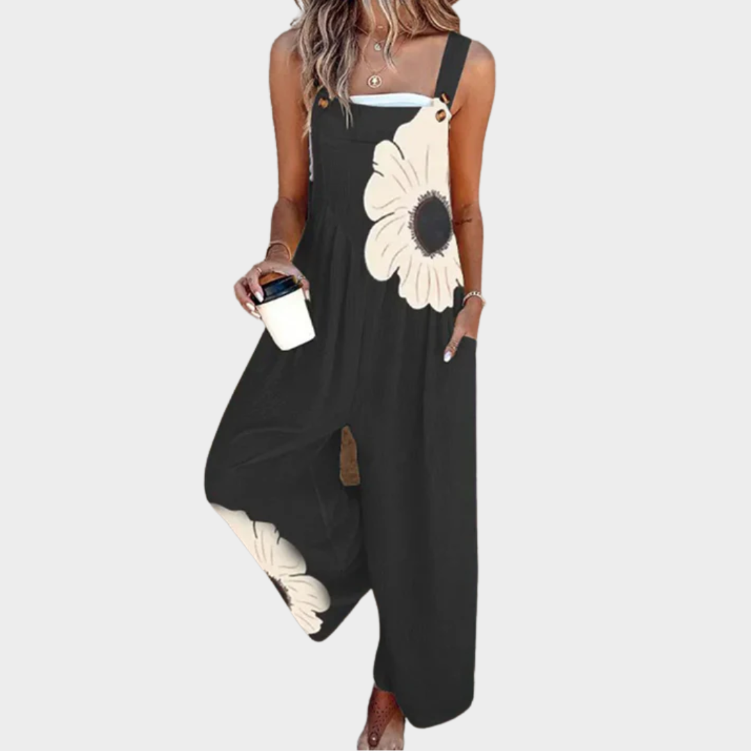 A woman wearing elegant black overalls with a single large cream bloom and adjustable straps.
