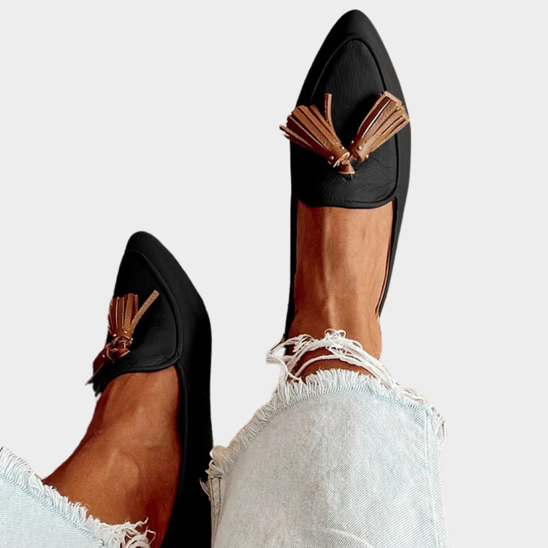 A woman wearing modern slip-on loafers with playful fringing, styled for an easy day in town.