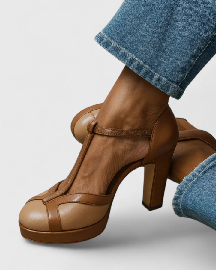 A woman wearing brown T-strap heels with a vintage round toe, stepping out confidently.