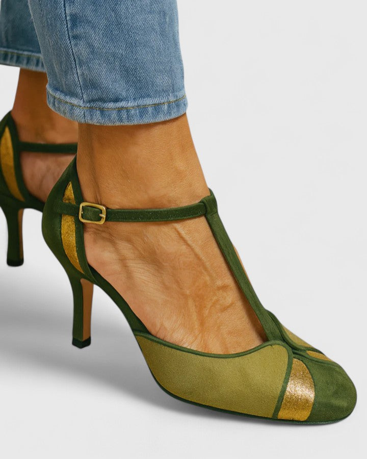 A woman wearing green T-strap heels with a rounded toe and gold trim, stepping out in a bright, elegant look.