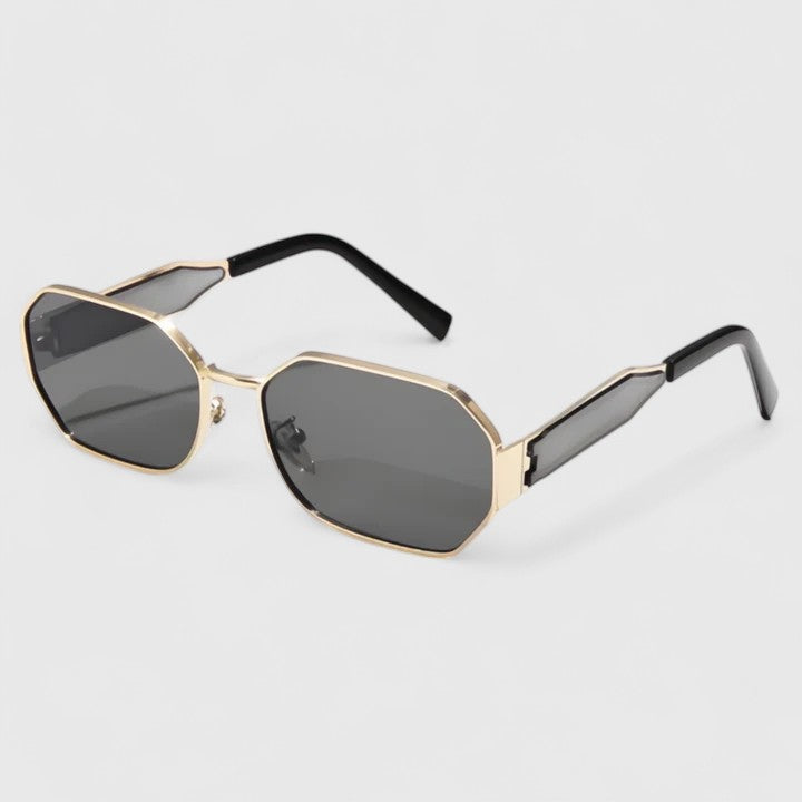 A woman wearing bold geometric gold-accented sunglasses with gradient lenses on a bright day.