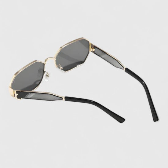 A woman wearing bold geometric gold-accented sunglasses with gradient lenses on a bright day.