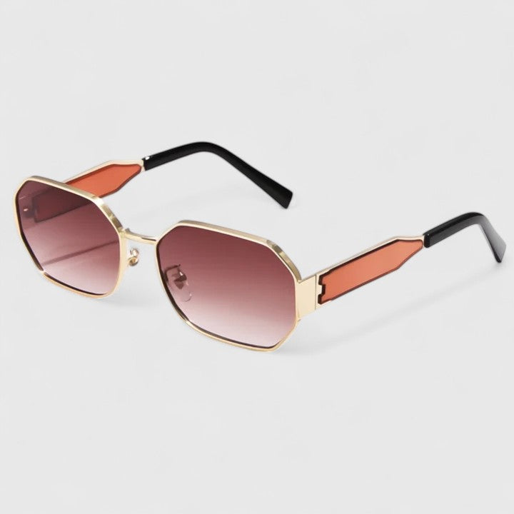 A woman wearing bold geometric gold-accented sunglasses with gradient lenses on a bright day.