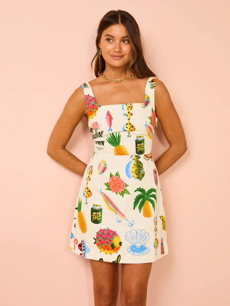 Woman on holiday wearing the Dorothy tropical print dress with a square neckline, standing in the sunshine.