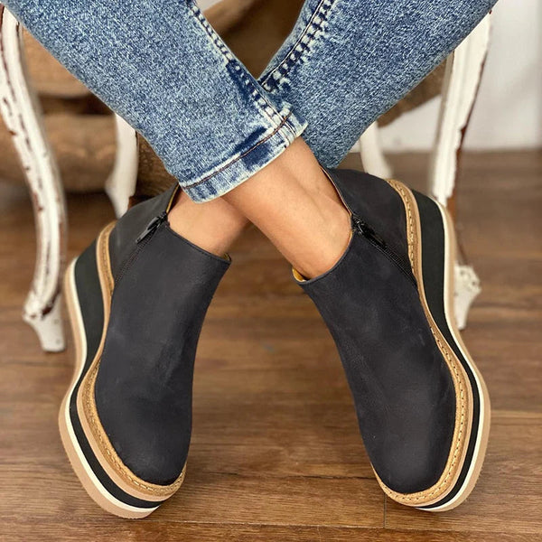 A woman wearing sleek minimalist ankle boots with jeans on a city break.