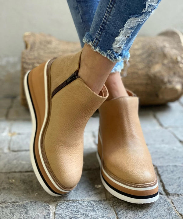 A woman wearing sleek minimalist ankle boots with jeans on a city break.