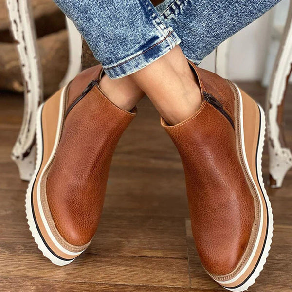 A woman wearing sleek minimalist ankle boots with jeans on a city break.