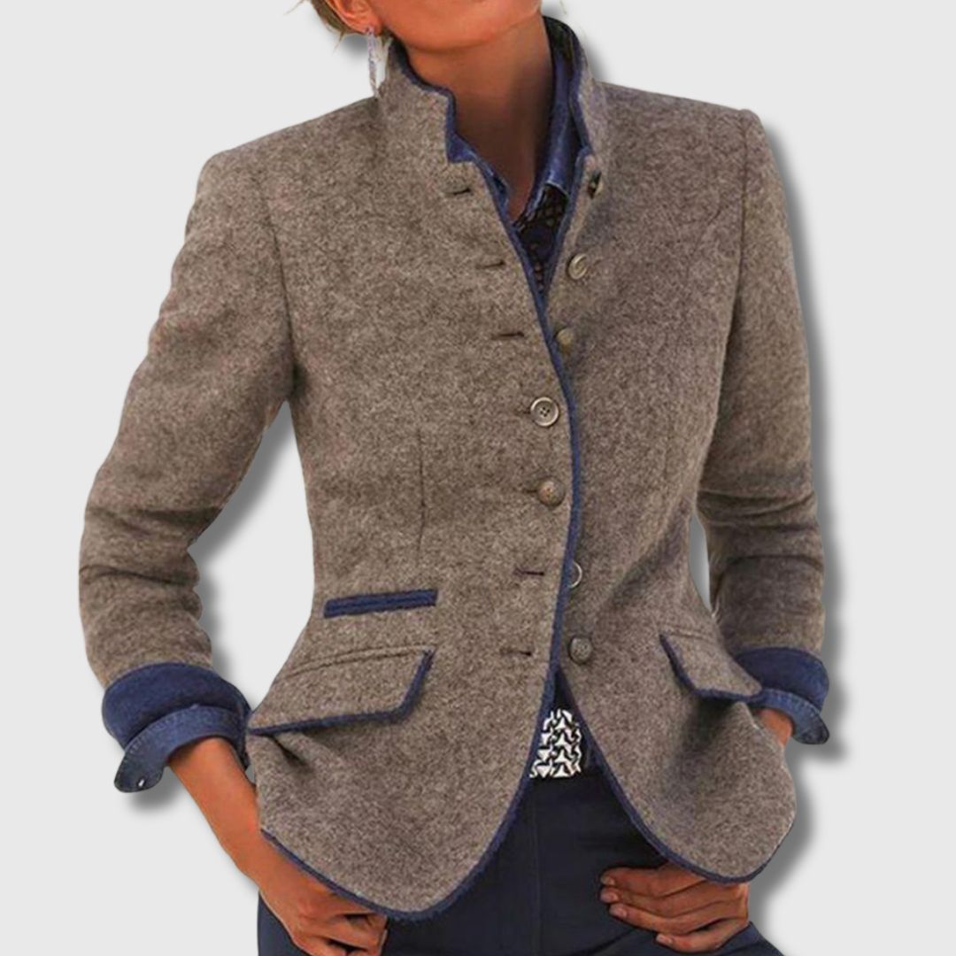 A woman wearing a structured tailored jacket with a defined waist over jeans, looking confident.