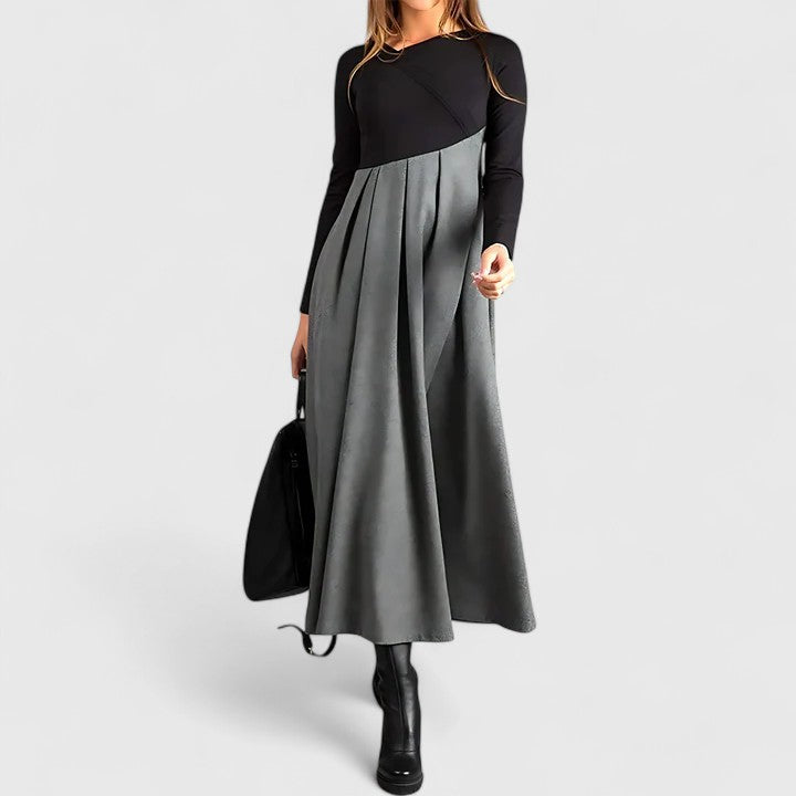 Woman wearing the Linda refined dress in black-grey, posing elegantly indoors.