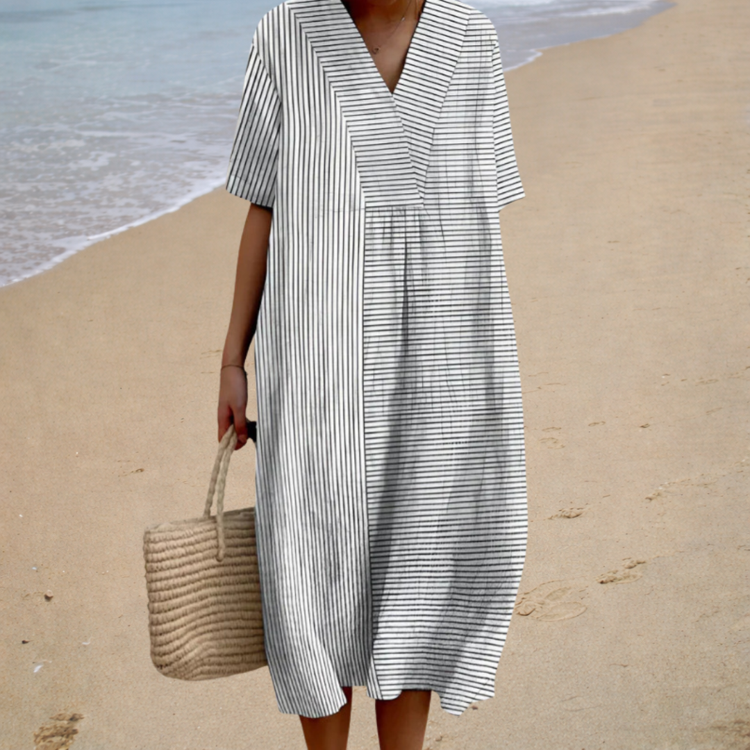 A woman wearing a flowing patterned summer dress on a bright day.
