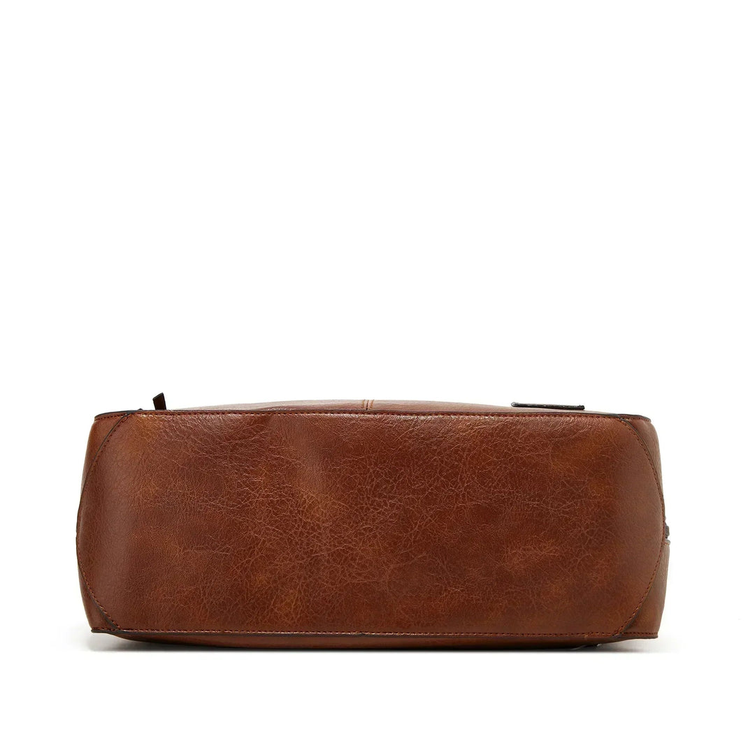 A soft brown vintage shoulder bag with zip pockets and tassel pulls, carried on the shoulder in town.