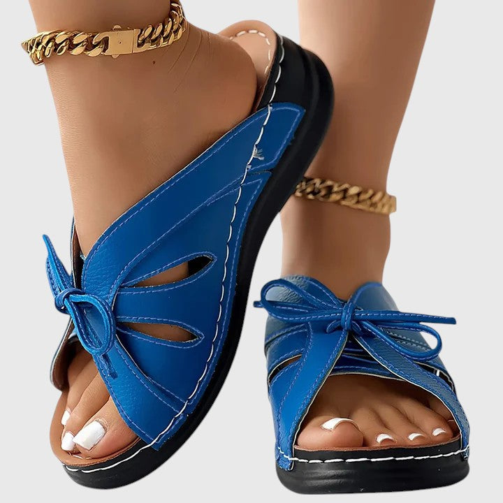 A woman in blue slip-on band sandals stepping out easily, feet cushioned and comfortable.