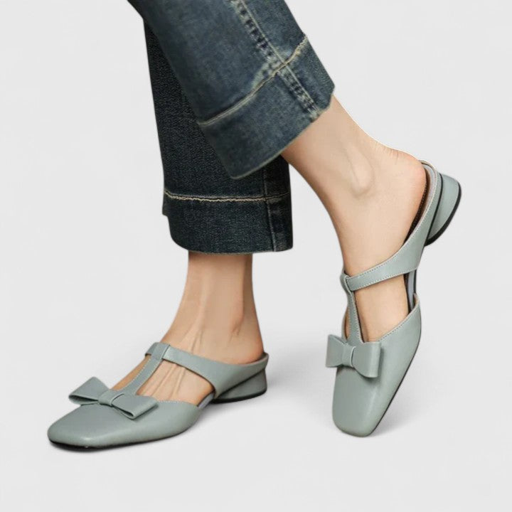 Soft green bow-detail mules with a slim T-strap, open back and a low heel.