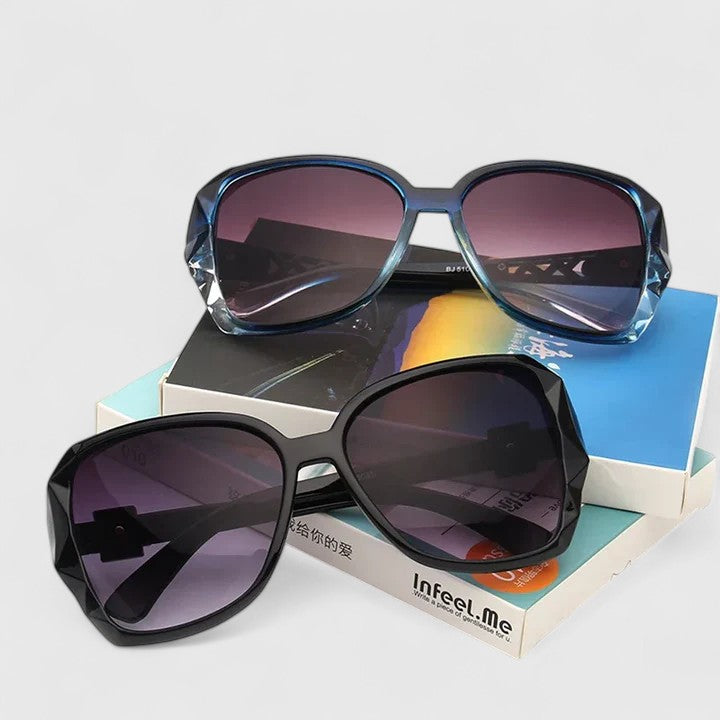 A woman on a sunny city street wearing chic square-frame sunglasses, smiling confidently.