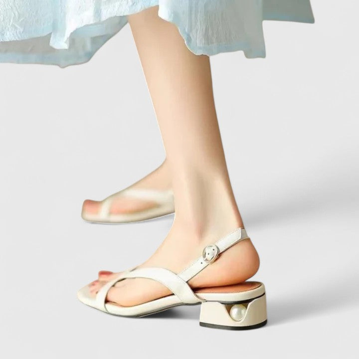 Cream toe-post sandals with a slingback buckle and a block heel set with a pearl.
