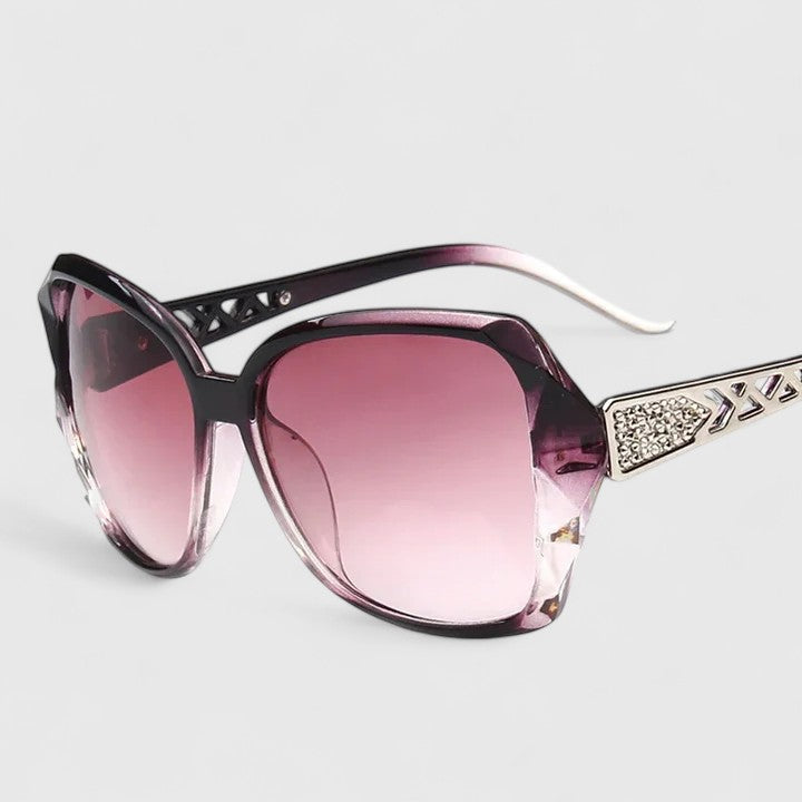 A woman on a sunny city street wearing chic square-frame sunglasses, smiling confidently.