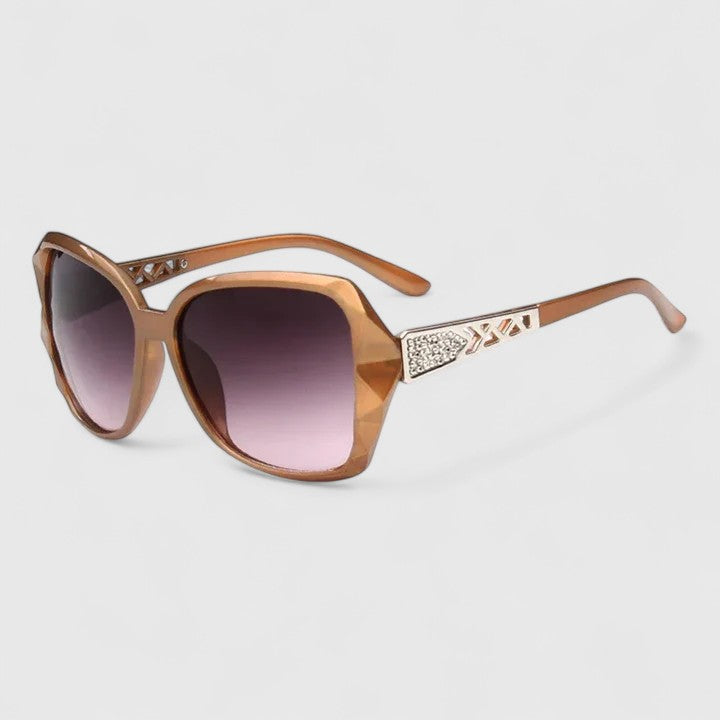A woman on a sunny city street wearing chic square-frame sunglasses, smiling confidently.